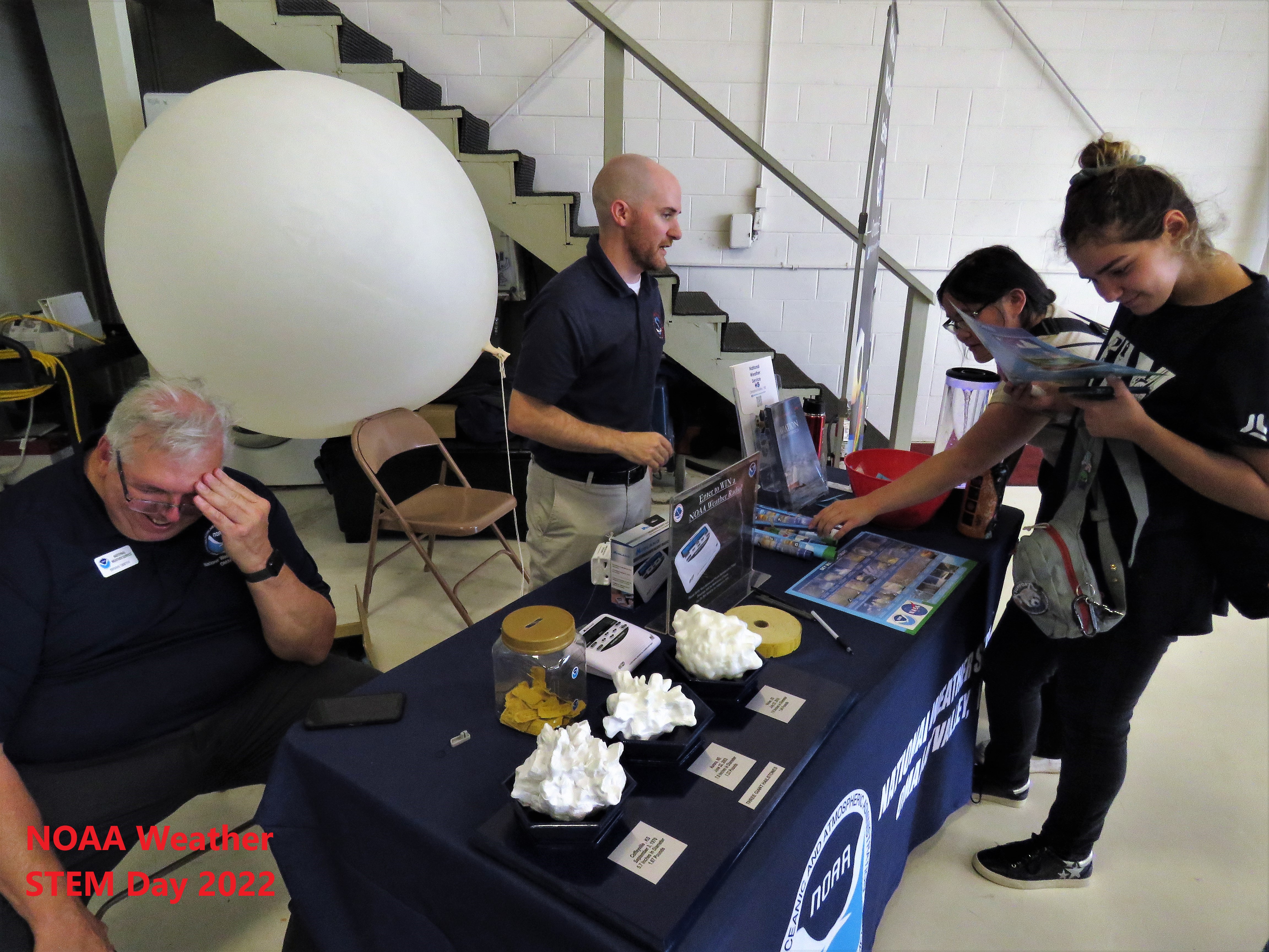 people at booth with weather baloon